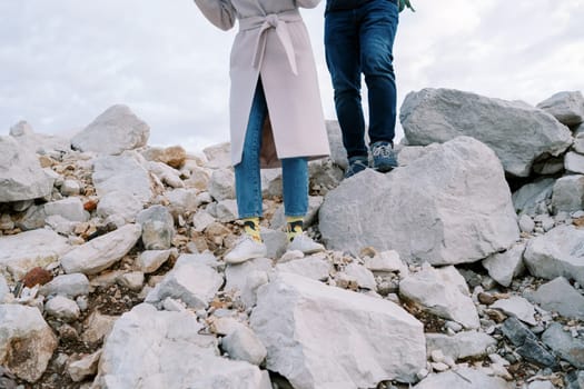 Man and woman are walking along a rocky slope. Cropped. Faceless. High quality photo