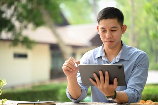 Handsome businessman using digital tablet at an outdoor table.