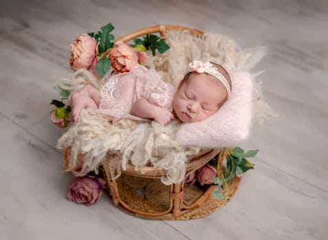 Newborn Girl In Pink Suit With Toy Cat Sleeps In Wooden Heart-Shaped Bowl During Professional Newborn Photoshoot