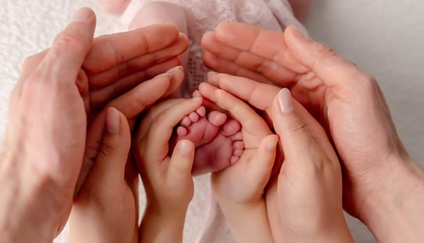 Mom, Dad, And Older Sister'S Hands Hold Newborn'S Feet In An Artistic Photo