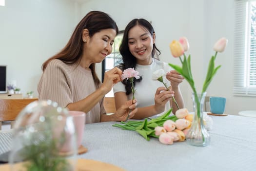 Mother and daughter arrange flower together at home on the weekend, family activities, mother and daughter do activities together on Mother's Day.