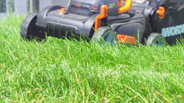 Castle Rock, Colorado, USA-June 25, 2023- At a residential suburban house, a lush green lawn is meticulously mowed using an electric lawn mower, creating a well-manicured and inviting outdoor space.