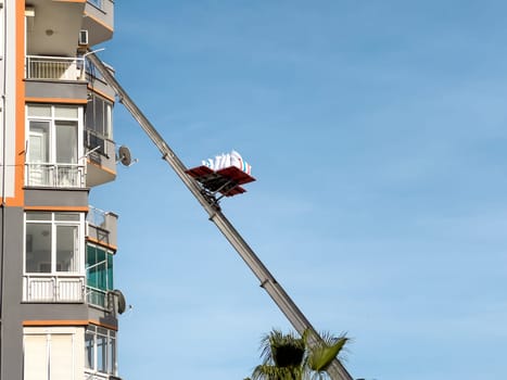 Home removal with hydraulic lift. Transporters carrying goods by elevator from the window of the building