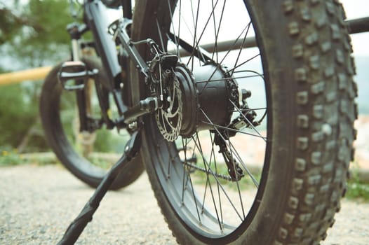 Details of a tubeless electric mountain bike tire wheel, standing on the the road trail. View from below. Low viewing angle. Selective focus