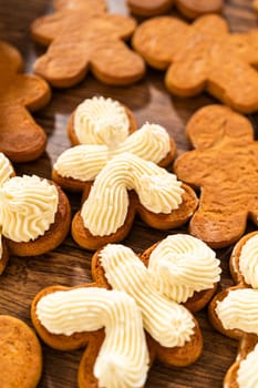 Making gingerbread man cookie sandwiches filled with eggnog buttercream, arrayed on a rustic wooden table, ideal for heartfelt Christmas gifting.