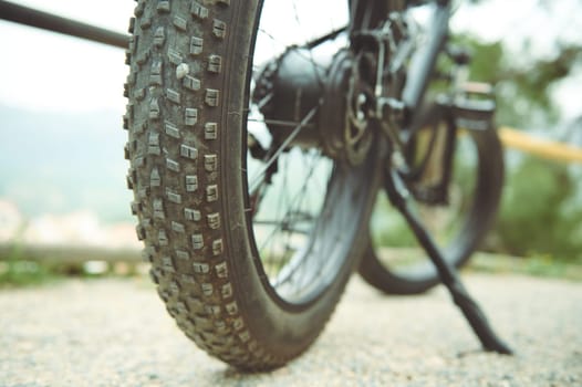 Details of a tubeless electric mountain bike tire standing on the side of the road. View from below. Low viewing angle. Selective focus