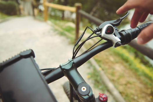Isolated bicycle brakes in male cyclist's hand. Adjusting bicycle hand brakes while riding, descending on the nature. Close-up view