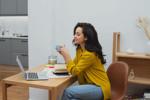 Thoughtful young woman in eyewear using computer while sitting on the sofa at home. High quality photo