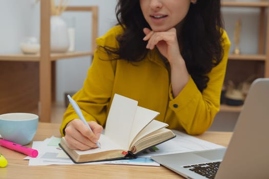 Thoughtful young woman in eyewear using computer while sitting on the sofa at home. High quality photo