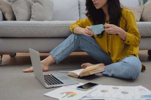 Thoughtful young woman in eyewear using computer while sitting on the sofa at home. High quality photo