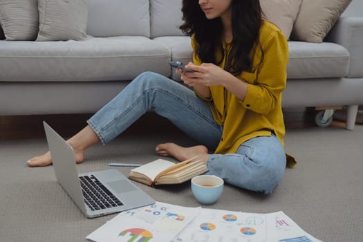 Thoughtful young woman in eyewear using computer while sitting on the sofa at home. High quality photo