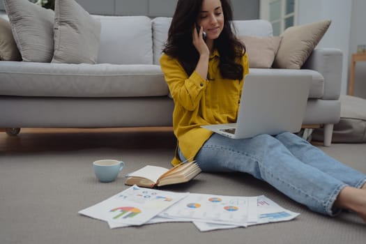 Thoughtful young woman in eyewear using computer while sitting on the sofa at home. High quality photo