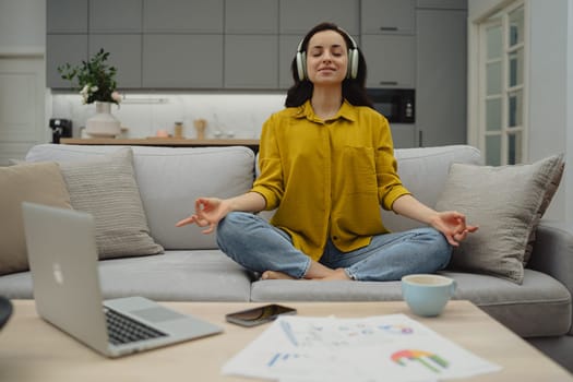 Thoughtful young woman in eyewear using computer while sitting on the sofa at home. High quality photo