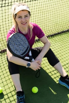 Sporty european woman padel tennis player trains on the outdoor court using a racket to hit the ball. High quality photo