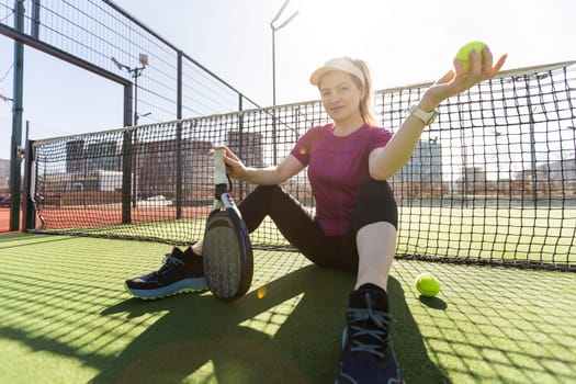 Sporty european woman padel tennis player trains on the outdoor court using a racket to hit the ball. High quality photo