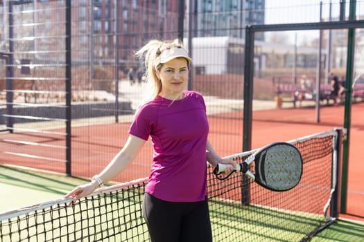 Happy female paddle tennis player during practice on outdoor court looking at camera. Copy space. High quality photo