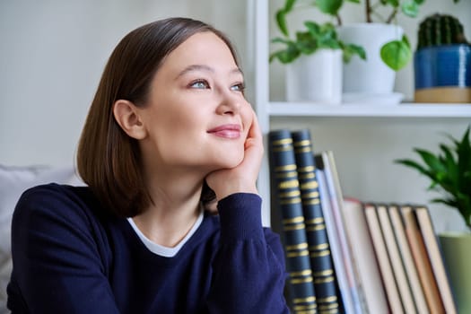 Portrait of young attractive smiling woman in home interior. Happy cheerful relaxed 20s female looking away, sitting on couch. Beauty, youth, happiness, health, lifestyle concept