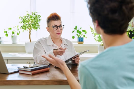 Middle-aged female professional psychologist mental therapist talking with young man in office. Psychotherapist advisor working with male patient. Psychology psychotherapy support treatment assistance