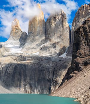 Granite peaks rise above a glacial lake under clear blue skies. torres del paine