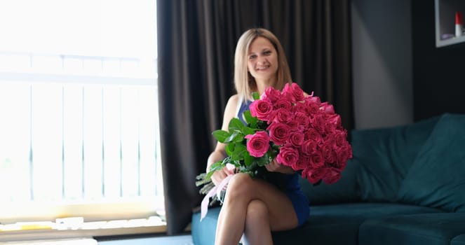 Young beautiful smiling woman is sitting with large bouquet of roses. Surprises for beloved women concept