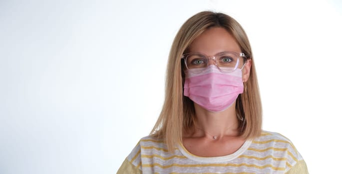 Portrait of young beautiful woman in pink protective medical mask and glasses. Mandatory mask mode concept