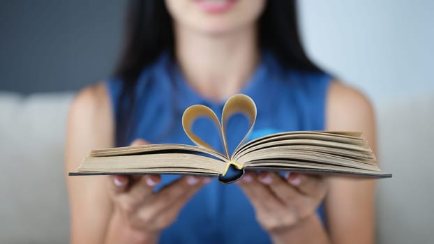 In female hands, book sheets are folded in shape of heart. Love to read concept