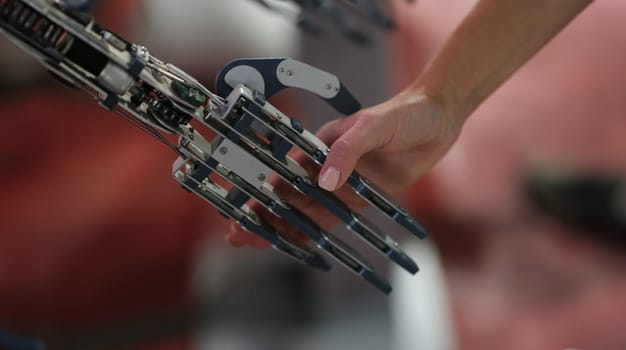 Woman shaking hand with metal prosthesis closeup. Modern prosthetics of limbs concept