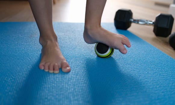 Child foot standing on small sports ball closeup. Prevention and treatment of flat feet in children concept