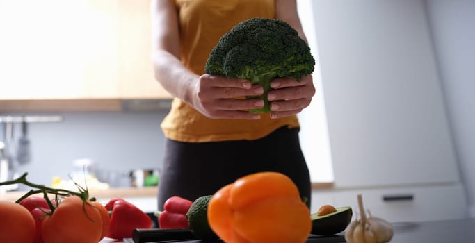 Female housewife holding broccoli in her hands in kitchen closeup. Proper nutrition for body shaping concept
