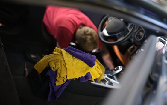 Man cleaning car interior at car wash. Dry-cleaning services car dealership concept