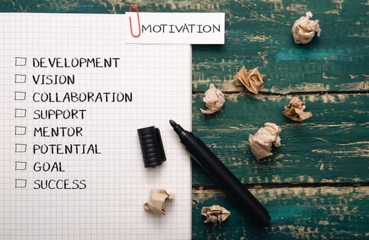 A piece of paper with a list of words and a black marker on it. The words are motivation, development, vision, collaboration, support, mentor, potential, goal, success, and progress
