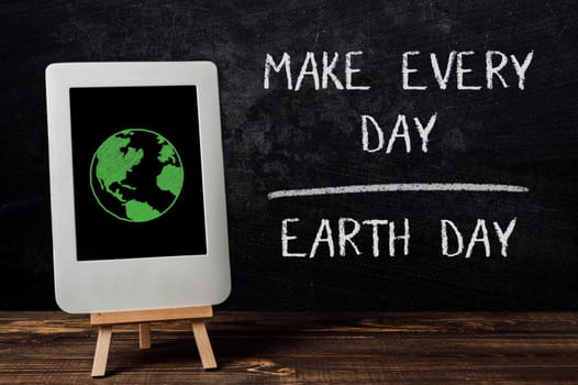 Make every day Earth Day. This is a chalkboard with a tablet on it. The tablet is green and the Earth is also green