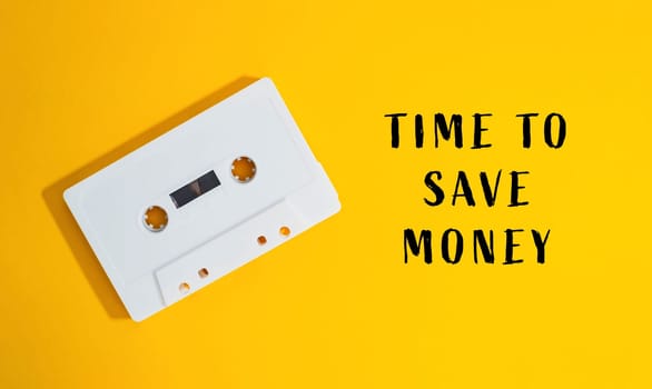 A white cassette tape is on a yellow background with the words Time to save money written below it