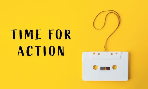 A white cassette tape is hanging from a string with a question mark on it. The words Time for Action are written below the tape