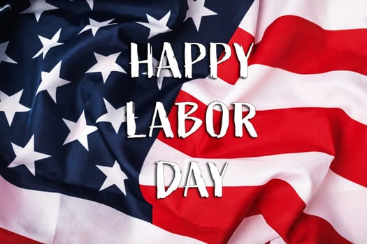 A red, white, and blue American flag with the words Happy Labor Day written below it. The flag is draped over a piece of cloth, giving it a sense of celebration and patriotism