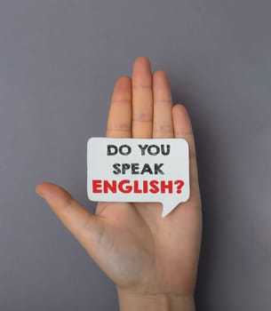A hand holding a sign that says Do you speak English. Concept of curiosity and interest in learning a new language