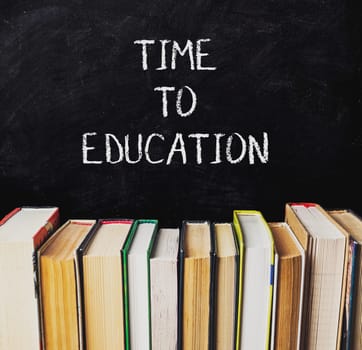 A chalkboard with the words Time to Education written on it. The chalkboard is covered with books, with some of them being green