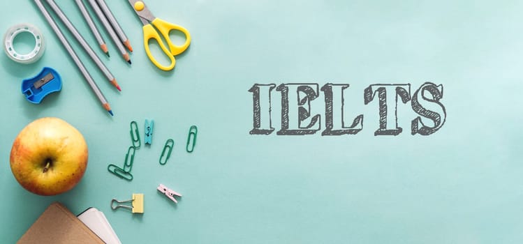 A green background with a bunch of school supplies and an apple. The word IELTS is written in white on the background