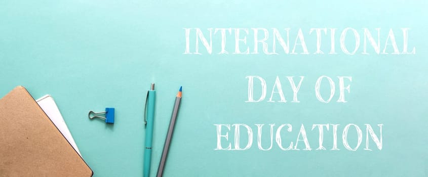 A blue background with a pencil and pen on it. The words International Day of Education are written below the pencils