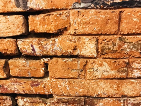 A brick wall with a lot of cracks and holes. The wall is brown and has a rough texture