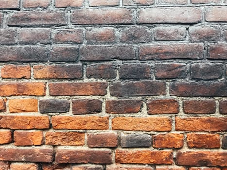 A brick wall with a brown and black color. The wall is made of bricks and has a rough texture