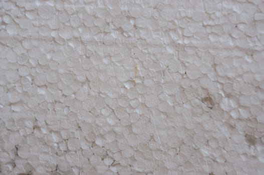 A white foam wall with a pattern of small white circles. The wall is covered in foam and has a rough texture