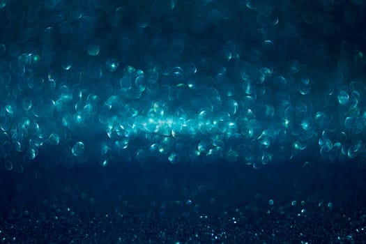 The image is a blue background with many small, round, and blurry dots. The dots are scattered throughout the image, creating a sense of movement and depth
