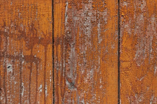 The wood grain is rough and the paint is peeling. The wood is old and has a rustic feel