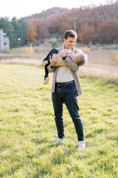 Smiling dad holding a little girl in his arms on a sunny autumn meadow. High quality photo