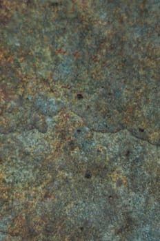 A close up of a stone wall with a greenish color. The wall has a rough texture and he is old