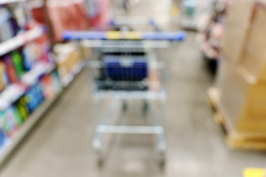Blurry shot of a shopping cart in a busy store aisle, showcasing the hustle and bustle of shopping activities.