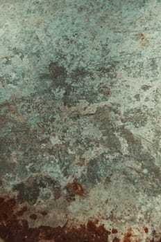 A wall with a greenish color and a rough texture. The wall has a lot of cracks and seems to be old