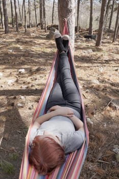 girl resting in a colorful hammock in the woods.