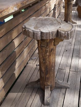 rustic handcrafted wooden bar stool on outdoor terrace.